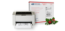 Printer with Click-N-Ship shipping label in printer tray beside Priority Mail shipping box.