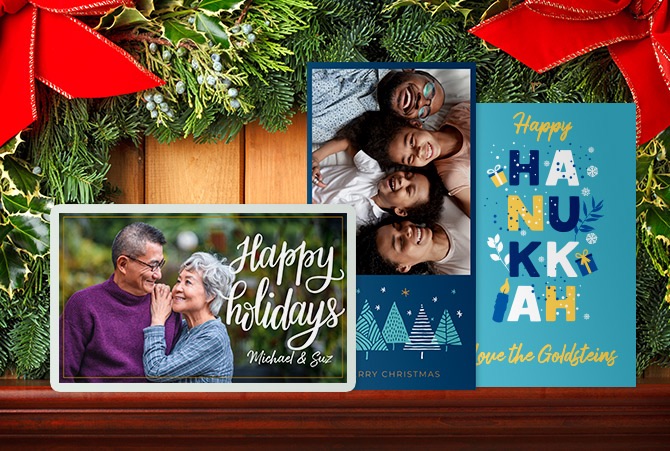 Custom holiday themed photo cards on a desk alongside a  pine bough.